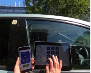 Photo of the outside car window with an embedded keypad device and a user typing