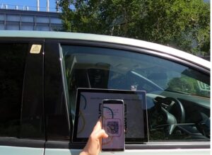 Photo of the outside car window with an embedded touchless device and a user connecting with a QR code